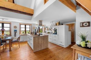 a kitchen with white cabinets and a wooden floor at Ostseedomizil II in Steinberg