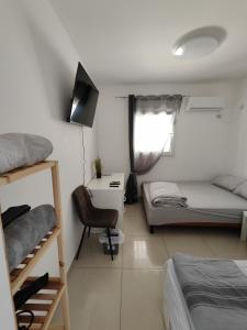 a bedroom with two beds and a desk and a television at Apartment with terrace and parking in Eilat