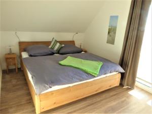 a bedroom with a wooden bed with a green pillow at FEWO Sterntaucher in Olpenitz