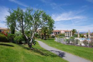 Villa Domaine du golf de Roquebrune في La Rouviere: ممر في ساحة بها شجرة وسياج