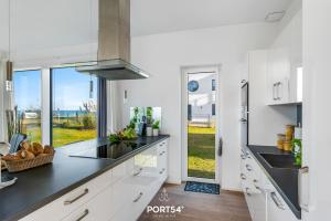 a kitchen with white cabinets and black counter tops at Villa du Soleil in Olpenitz