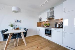 a kitchen with white cabinets and a wooden table at Marina Sunset West in Olpenitz