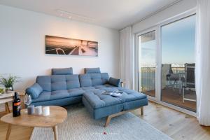 a living room with a blue couch and a table at Marina Sunset West in Olpenitz