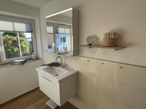 a white bathroom with a sink and a mirror at Stuuv dree in Gelting