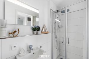 a white bathroom with a shower and a sink at Maison de la mer in Olpenitz +27 photos