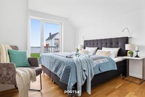 a bedroom with a bed with a blue blanket and a chair at Ahoi Lodge in Olpenitz