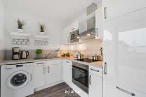 a white kitchen with a washer and dryer at Ahoi Lodge in Olpenitz