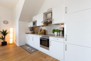 a kitchen with white cabinets and stainless steel appliances at Hafenwelt in Olpenitz