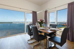 una sala da pranzo con tavolo, sedie e ampie finestre di Hafenwelt a Olpenitz