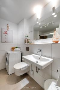 a white bathroom with a toilet and a sink at Seestern in Olpenitz