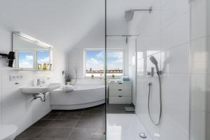a white bathroom with a tub and a sink at Viktoria´s Baltic Lounge in Olpenitz