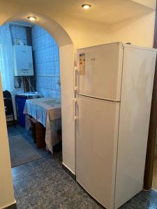 a white refrigerator in a kitchen with a table at Apartament parter in Craiova