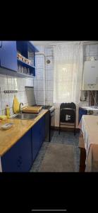 a kitchen with blue cabinets and a sink and a table at Apartament parter in Craiova