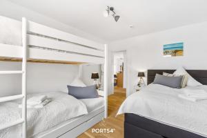 a white bedroom with two bunk beds in it at Captainslodge in Olpenitz
