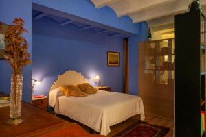 1 dormitorio con cama blanca y pared azul en Ca la Cèlia -Loft, en Maçanet de Cabrenys