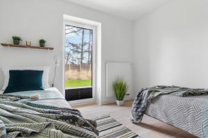 a white bedroom with a bed and a window at Flaute in Sankt Peter-Ording