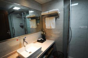 ein Bad mit einem Waschbecken, einer Dusche und einem Spiegel in der Unterkunft Chongqing Jianfeng Hotel in Fuling