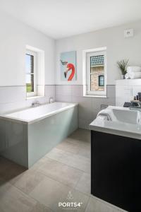 a white bathroom with a large tub and a sink at Flamingo Bay in Osterhever