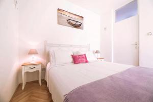 um quarto com uma grande cama branca e uma almofada vermelha em Apartment DORA Split em Split