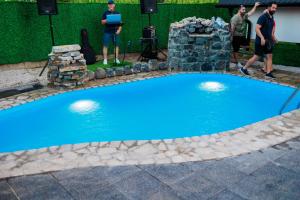 two men standing next to a blue swimming pool at Resort La Familia in Bihać