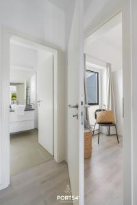 Cette chambre blanche dispose d'une porte menant à une salle de bains. dans l'établissement Ferienwohnung Freiherr, App 8 Emmelsbüll, à Emmelsbüll-Horsbüll