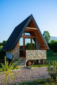 een klein huis met een zwart dak en een stenen muur bij Resort La Familia in Bihać