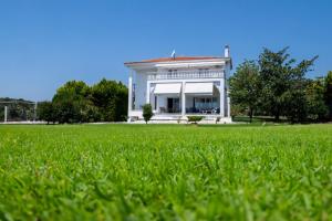 a white house with a lawn in front of it at Villa Mae in Elaiokhórion