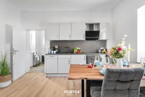 a kitchen with white cabinets and a wooden table at Strandmuschel Gelting in Gelting