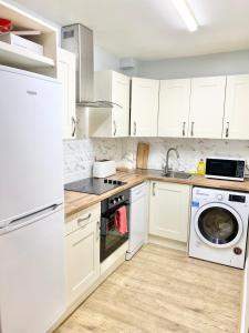 een keuken met witte kasten en een wasmachine en droger bij Lovely 2 bedroom apartment in Dublin City in Dublin