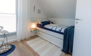 - une chambre avec un lit doté d'une couverture bleue et d'une fenêtre dans l'établissement Seestern Büsum, à Büsum