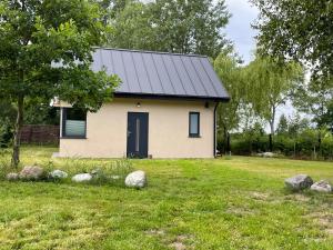 mały biały dom z czarnym dachem w obiekcie Domek pod Debami w mieście Choczewo