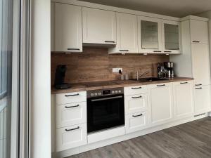 eine Küche mit weißen Schränken und einem schwarzen Backofen in der Unterkunft Salzwiesenblick in Büsum
