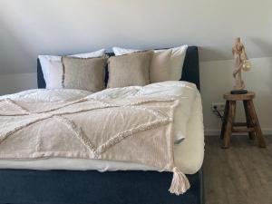 ein Bett mit weißen Laken und Kissen darauf in der Unterkunft Salzwiesenblick in Büsum