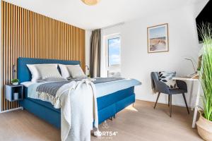 ein Schlafzimmer mit einem blauen Bett und einem Stuhl in der Unterkunft Strand Loft in Olpenitz