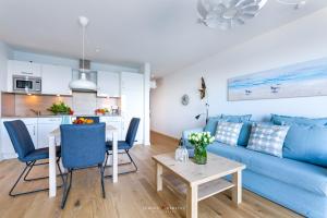 a living room with a blue couch and a table at Marinablick in Olpenitz