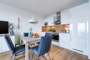 a kitchen with a wooden table and blue chairs at Marinablick in Olpenitz