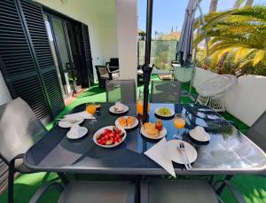 einen Tisch mit Speisen und Getränken auf dem Balkon in der Unterkunft Aldeamento Praia dos Beijinhos in Porches