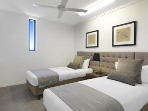 a bedroom with two beds and a ceiling fan at Oaks Mackay Carlyle Suites in Mackay