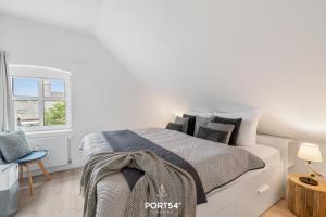 une chambre blanche avec un lit et une chaise dans l'établissement Ferienwohnung Grüne Freiheit, App 14 Emmelsbüll, à Emmelsbüll-Horsbüll