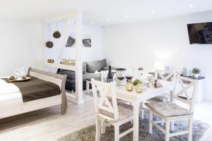 a white bedroom with a bed and a table and chairs at Biberburg in Flensburg