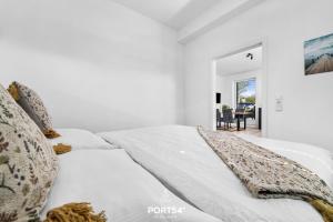 a white bedroom with a bed and a dining room at Strandperle Gelting in Gelting