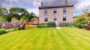 an old stone house with a large lawn at Nidd House Farm in Harrogate