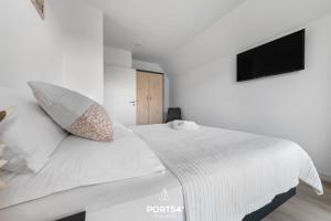 a white bedroom with a bed and a tv at Ferienhaus Frische Brise in Büsum