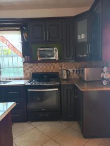 a kitchen with black cabinets and a stove and a microwave at BelleAir Views in Gros Islet