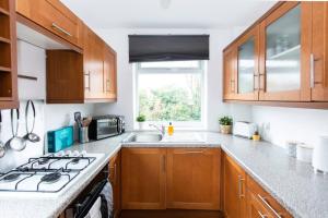 a kitchen with wooden cabinets and a stove top oven at Charming 3-Bed Retreat, Excellent Locaton in Nottingham