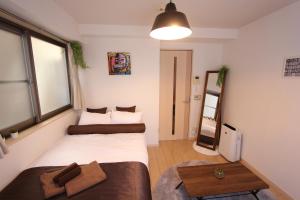 Habitación pequeña con 2 camas y mesa. en Luana Hotel ベルビ早稲田, en Tokio