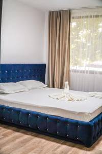 ein großes Bett mit einem blauen Kopfteil und einem Fenster in der Unterkunft Hotel & MedSpa Siret in Mamaia