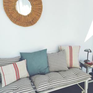 um sofá com almofadas e um espelho na parede em La Zagala em Badajós