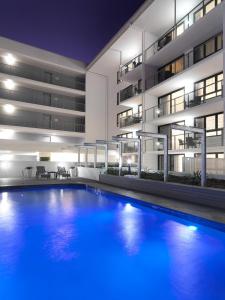 a swimming pool in front of a building at night at Oaks Mackay Carlyle Suites in Mackay