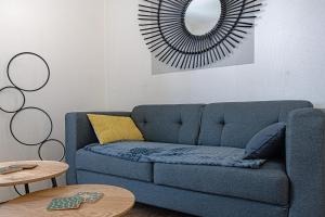 a blue couch in a living room with a mirror at Le pied à terre d'ernest in Limoges